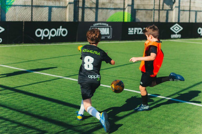 crianças jogando bola em campo de futebol