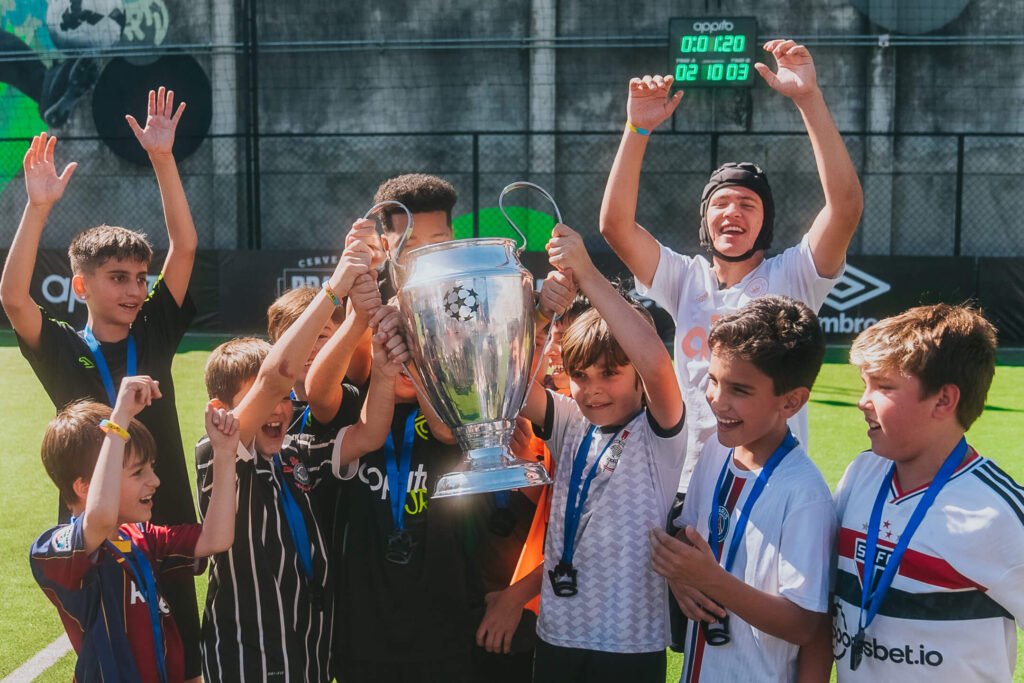 crianças comemorando com um troféu após partida de futebol