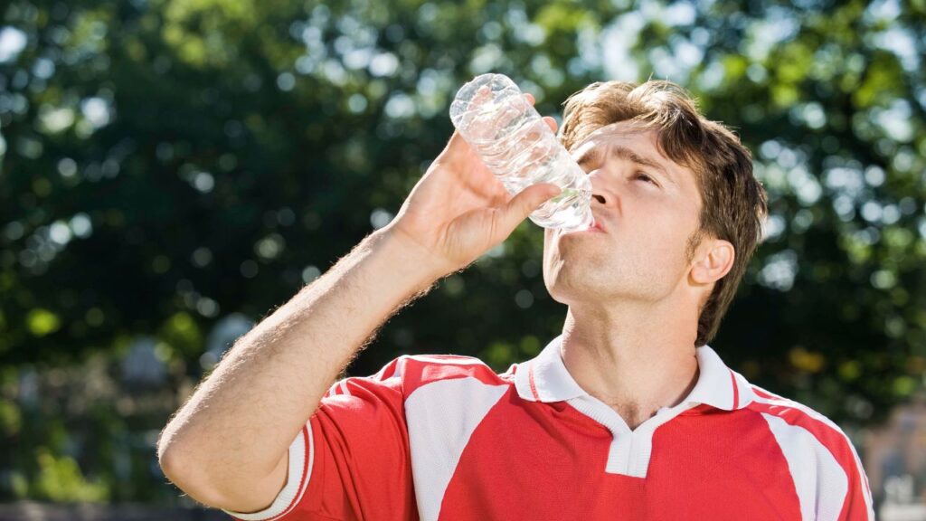 homem se hidratando após partida de futebol