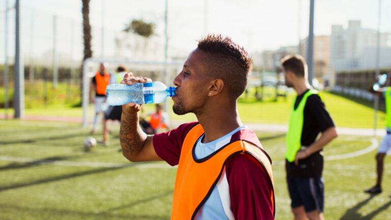 homem bebendo agua durante jogo de futebol