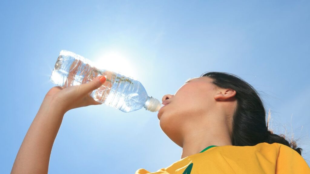 mulher bebendo agua durante jogo de futebol