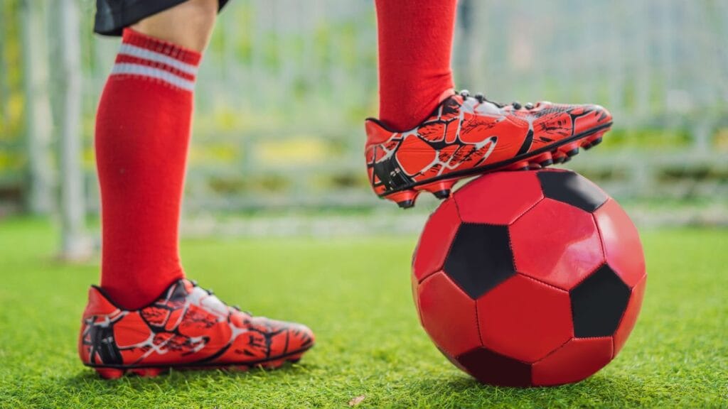 criança segurando a bola com o pé