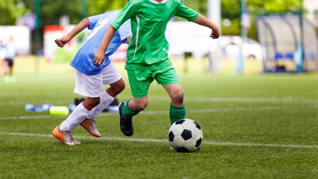 crianças jogando futebol num campo