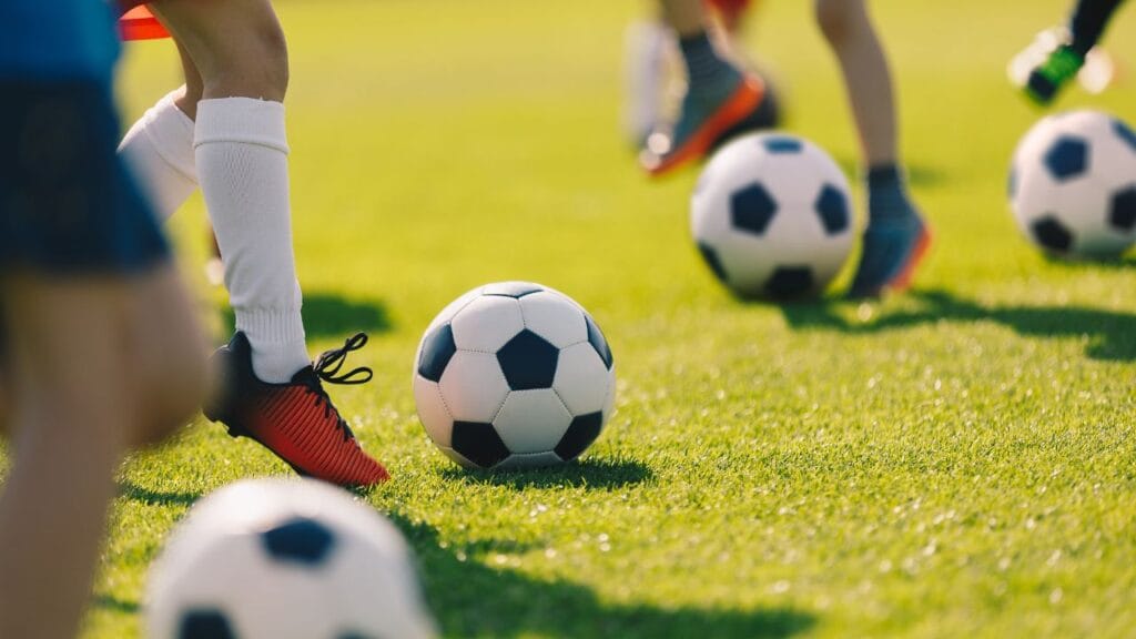 varias bolas de futebol na grama do campo